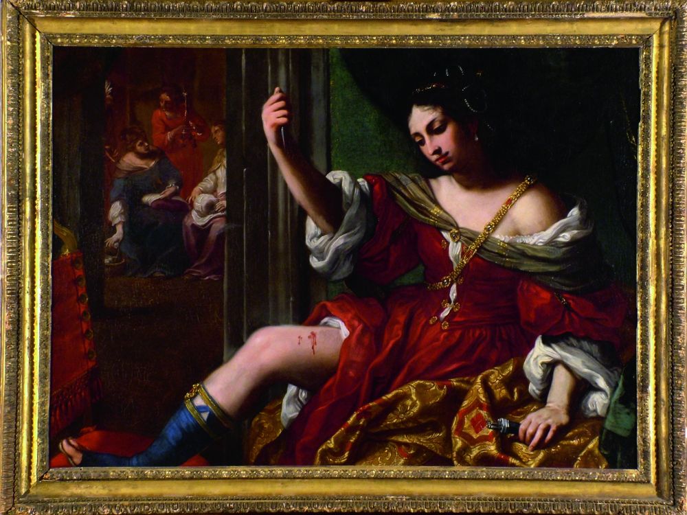 A woman clothed in a red gown lifts her bare thigh, which she has just stabbed with a knife