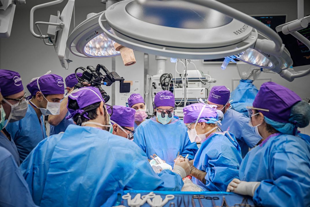 Many surgeons wearing blue scrubs and purple hats