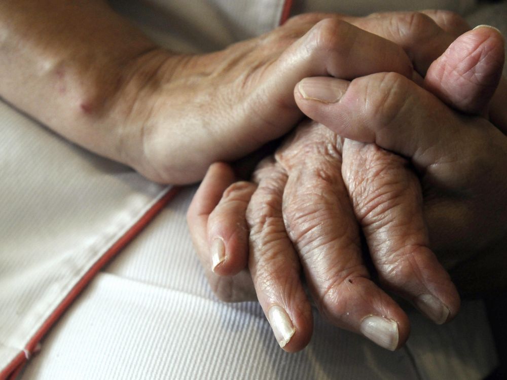 A nurse's hands hold those of an older person with Alzheimer's