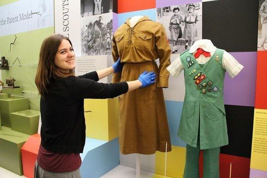 Curator removing two dresses from forms in an exhibition