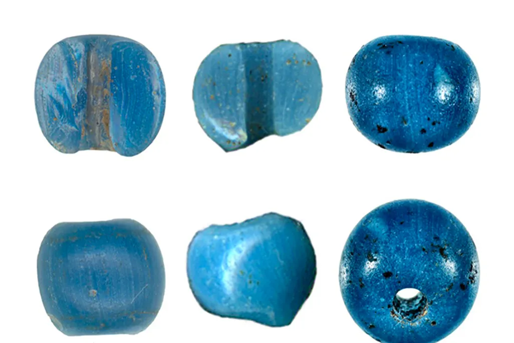 Six small bright, light blue beads, some all the way intact and some halved to reveal their small middle hole