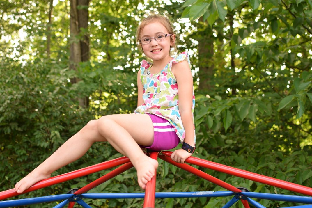 A Girl Stops For A Smile Atop The Jungle Gym 