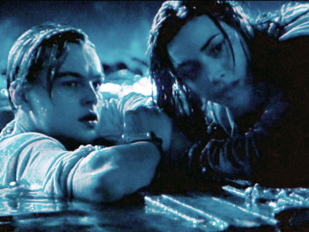 A still from Titanic showing Rose atop the board and Jack clinging to the side