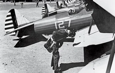 Students, wearing parachutes, preflight an endless lineup of Stearmans.