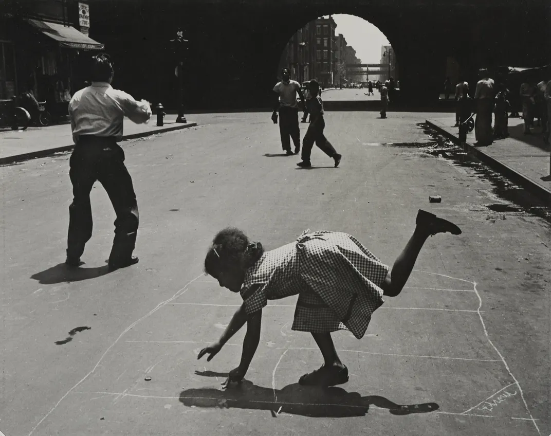 A black and white photo showing children playing in the street