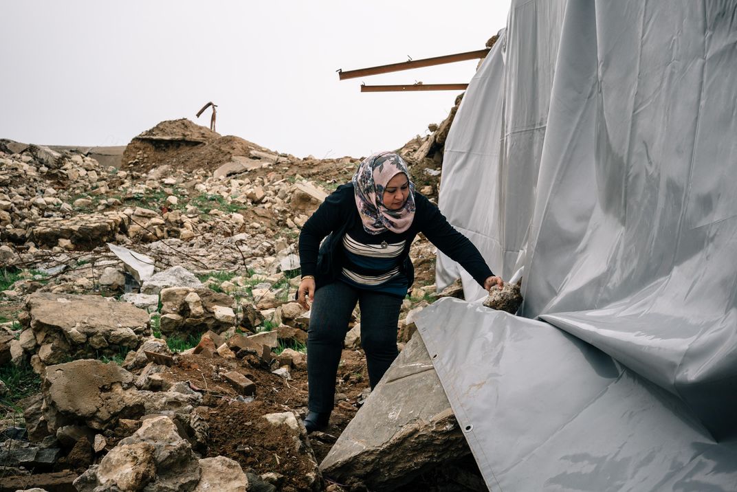 Layla Salih secures a tarp over the remains of sculptures and inscriptions damaged by Islamic State militants in Nimrud.