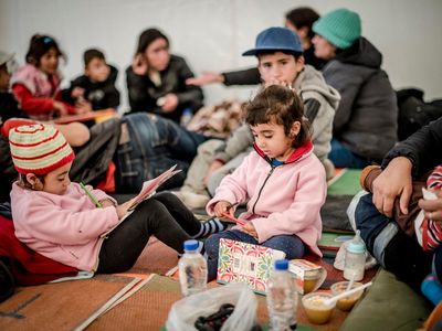 Young Syrian refugees play with donated paper and pens in the former Oxy transit camp in Lesvos, Greece.