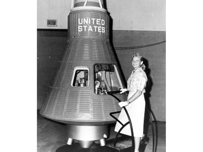 Jerrie Cobb stands before a Project Mercury space capsule in heels and gloves. What you can't see: inside the capsule, a male mannequin lies in the place where an astronaut eventually would. The FLATs were never seriously considered for astronaut positions.