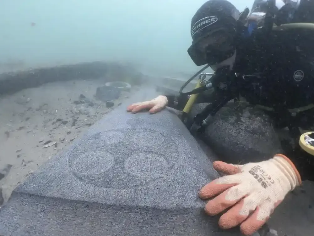 A marine archaeologist examines one of the engraved Purbeck gravestones recovered from the 13th-century Mortar Wreck
