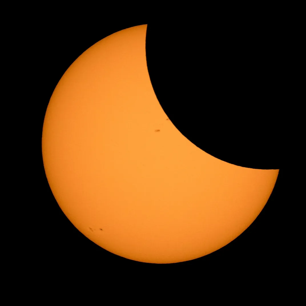 the sun appears as a thick crescent shape, partially blocked by the moon