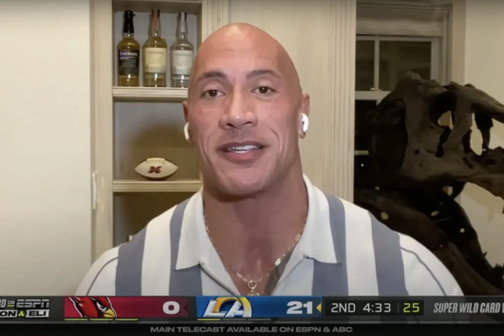 An image of Dwayne "The Rock" Johnson in a virtual call for ESPN's "ManningCast" show. Behind the actor is a T.rex skull.