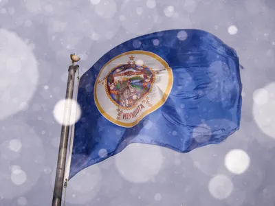 The current Minnesota flag, which lawmakers hope to soon retire, flies during a snowstorm.