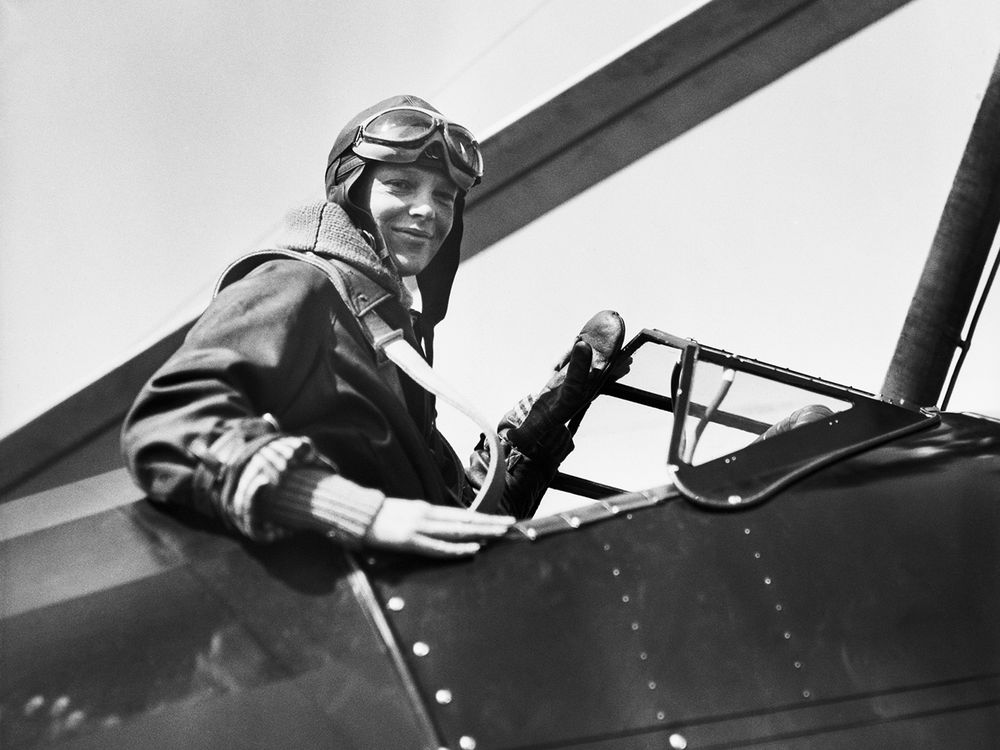 Amelia Earhart in a plane, wearing her flying cap