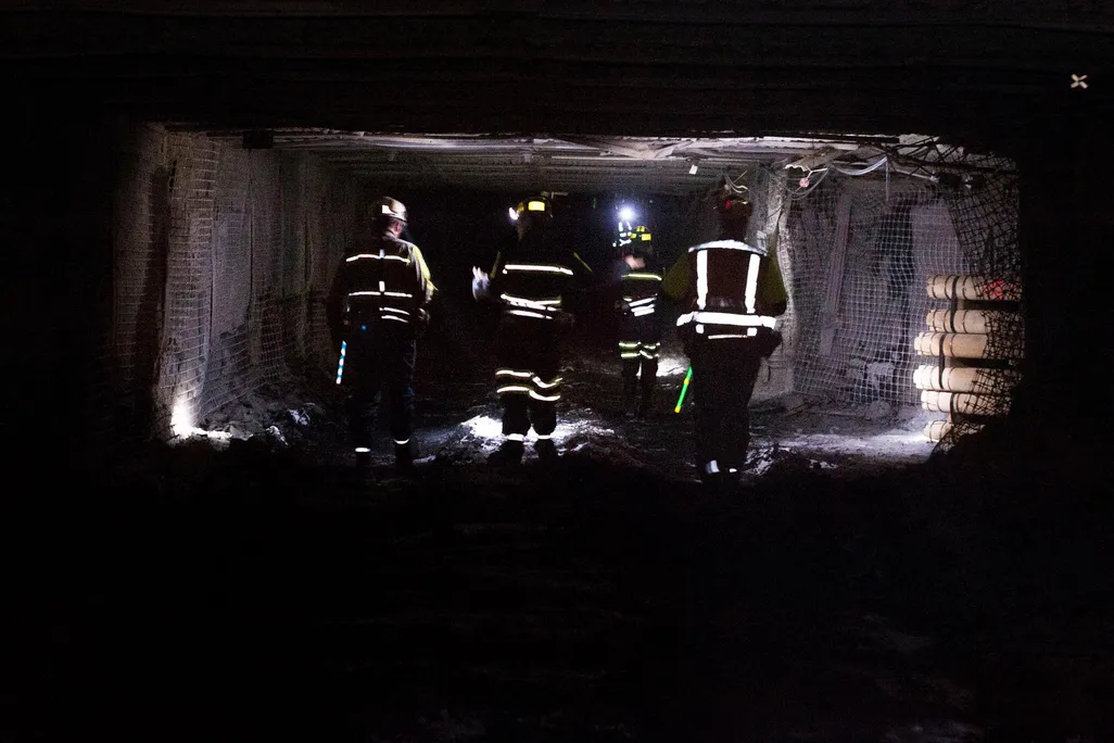 Coal miners dramatically walk through a tunnel