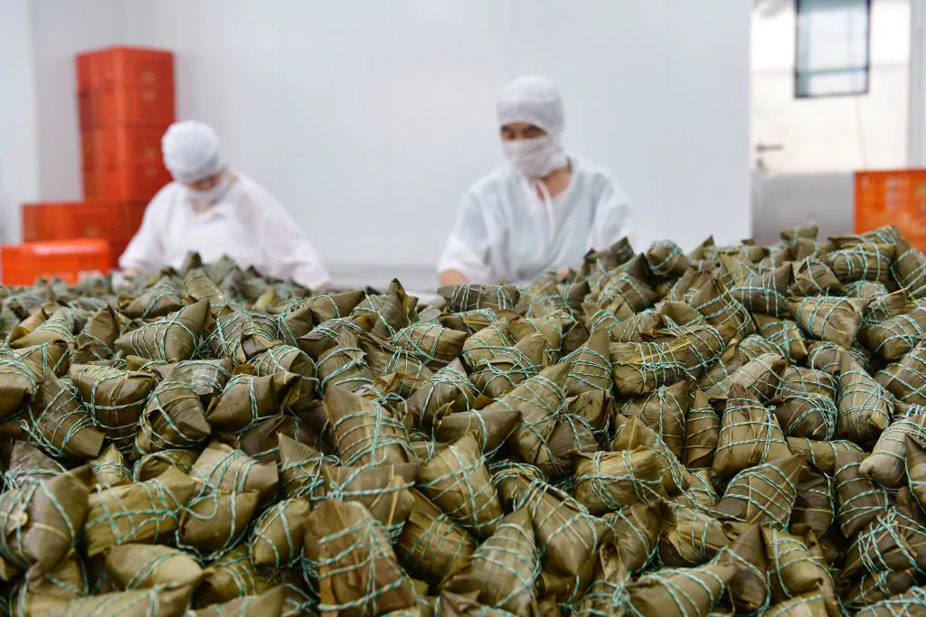 Employees pack cooked zongzi at a food factory in Yichang, Hubei Province in China