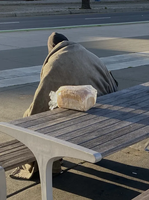 A person wrapped in blanket behind a loaf of bread thumbnail