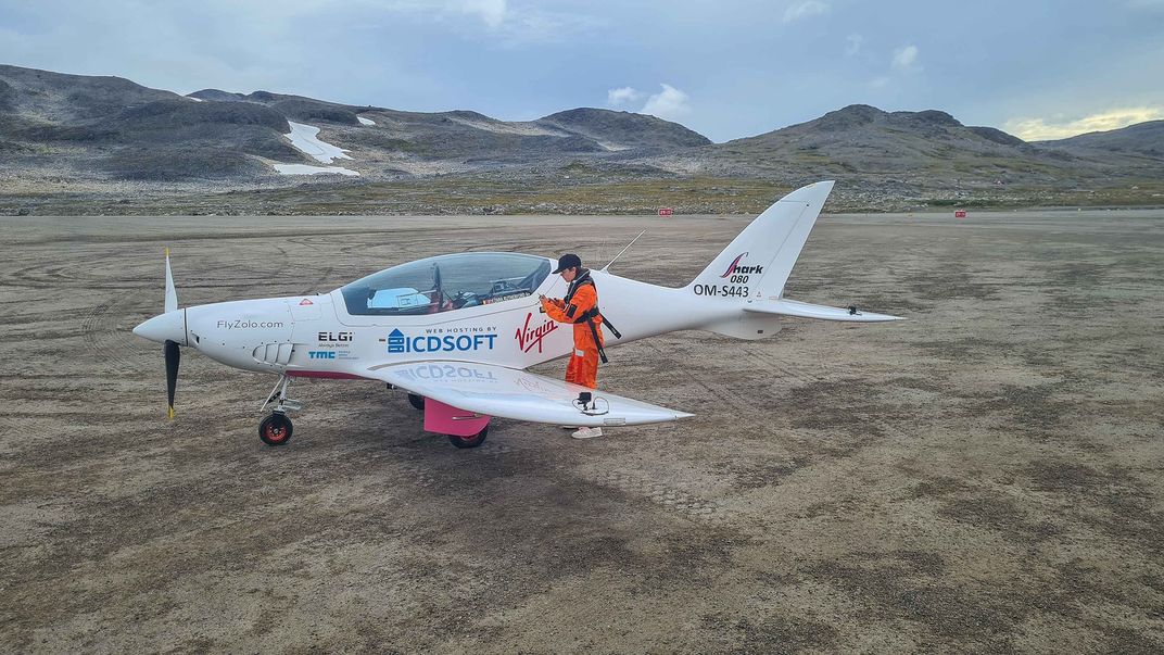 woman in front of small plane in orange jumpsuit