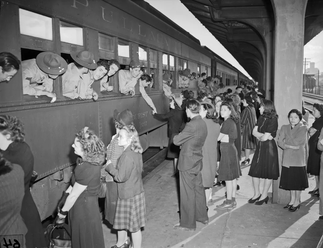 Black and white photo of people saying goodbye to loved ones onboard a train