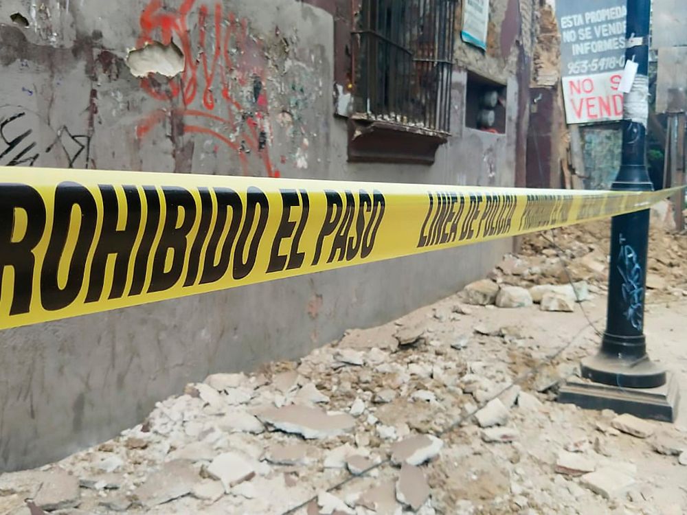 Debris covers a street in Oaxaca. Caution tape reads "Prohibido el paso - linea de policia"