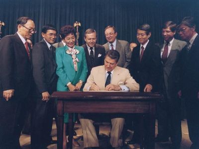 Ronald Reagan signing the Civil Liberties Act of 1988 that apologized for the internment of Japanese American citizens and permanent residents during World War II.