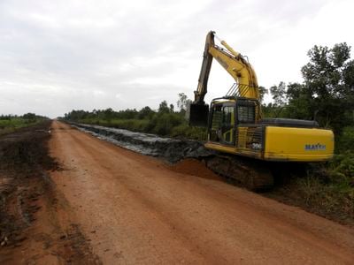 Seen in 2012, an excavator works on a road near an Indonesian oil palm plantation built on disputed lands once home to a rainforest.