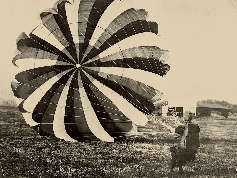 A woman holding the strings to a parachute canopy, having just landed