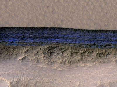 Underground ice exposed on a steep Martian slope appears bright blue in this enhanced-color view from NASA's High Resolution Imaging Science Experiment (HiRISE) camera in Mars orbit.