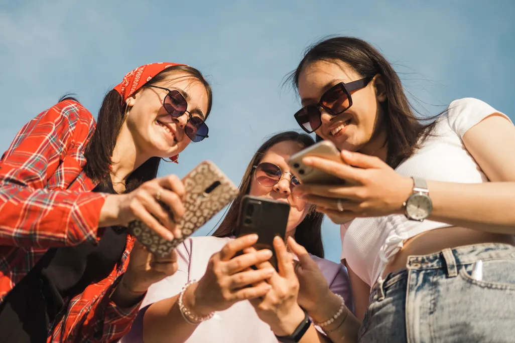 three young adults holding smartphones