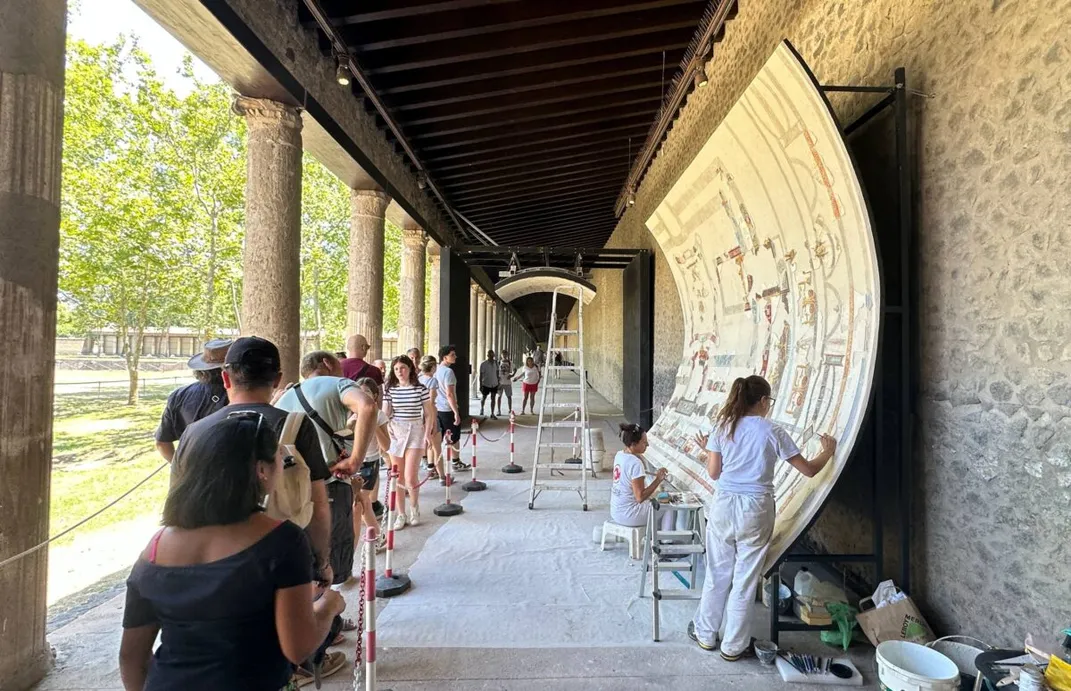 Travelers watching archaeologists restore a ceiling fresco