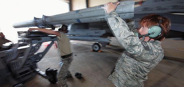 Staff Sergeant Michelle Torrey, right, with Master Sergeant Brett Kitzman load an AIM-120 missile onto an F-16.