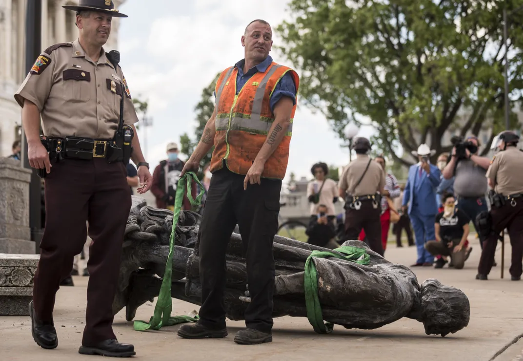 A worker prepares to take the toppled Columbus statue away