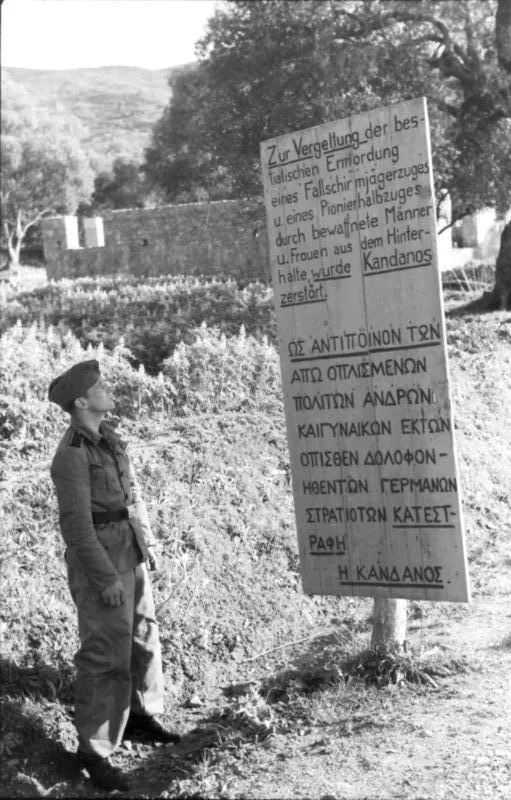 A German soldier in front of a sign erected by the Nazis after the razing of Kandanos