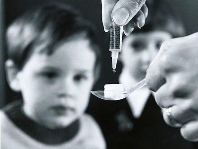 Though acute flaccid myelitis is not nearly as widespread as polio was at the height of its outbreaks, nor is the polio virus present in patients with AFM, yet symptoms, including paralysis, starkly resemble the disease. Pictured: Child gets polio vaccine on sugar cube circa 1970s. 