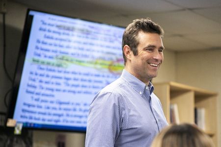 Man stands in front of screen with a chapter of a book on it and highlighted text