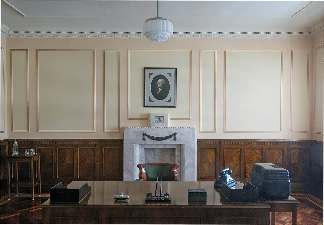 a boardroom with a portrait of George Washington over a fireplace