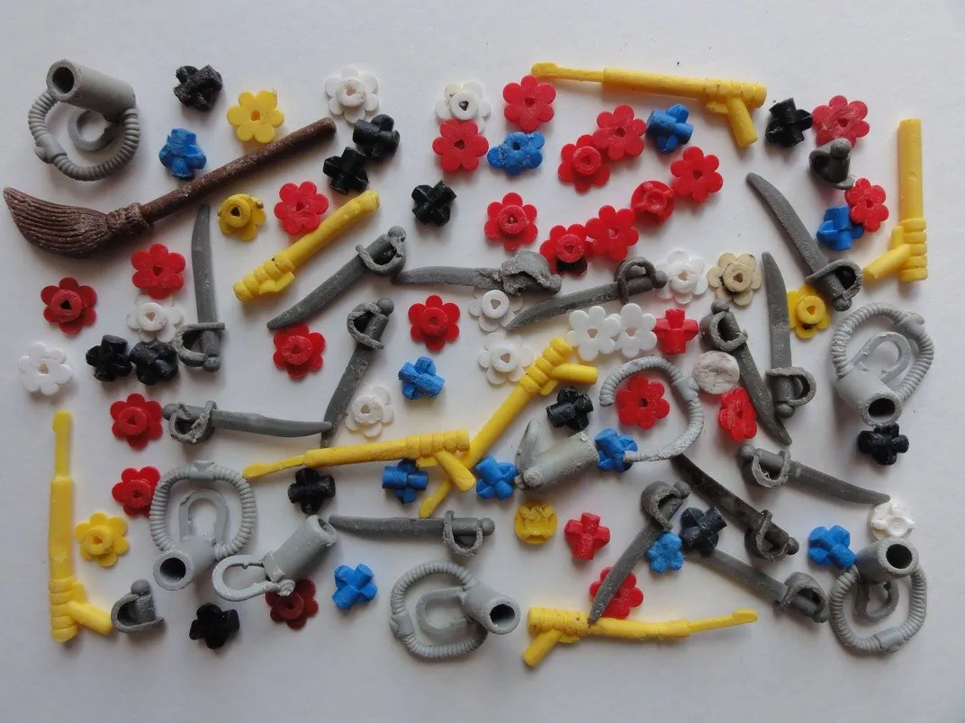 An image of small plastic lego pieces against a white background. Some are in the shape of flowers.