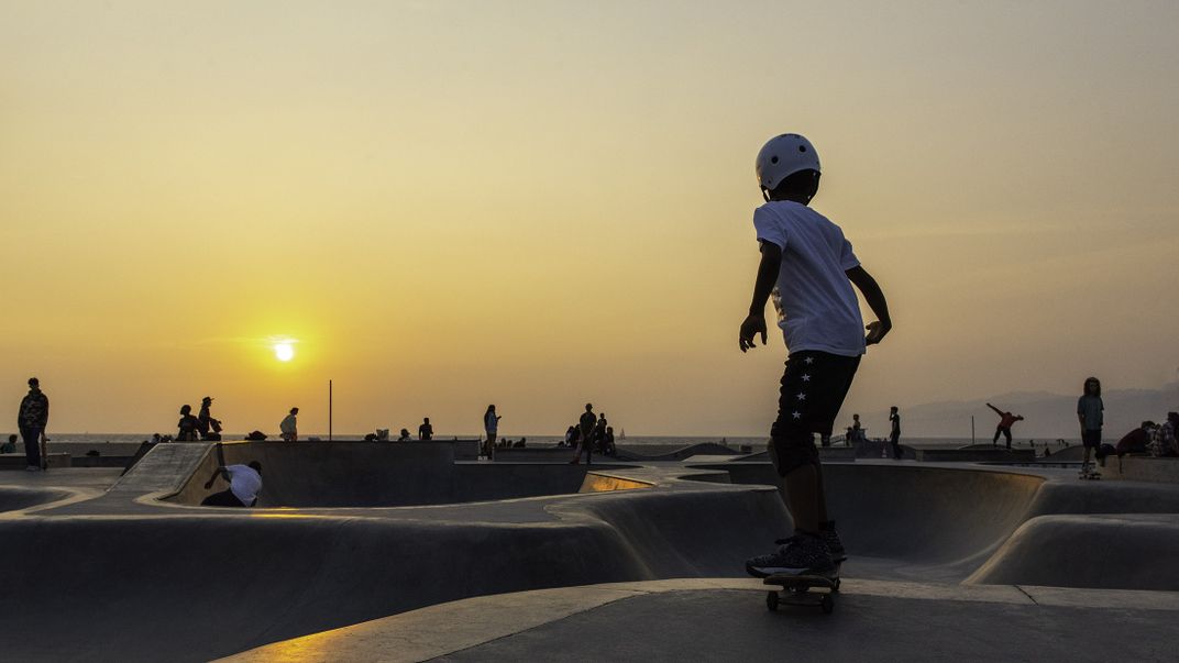 A young kid skateboards at the skatepark at sunset
