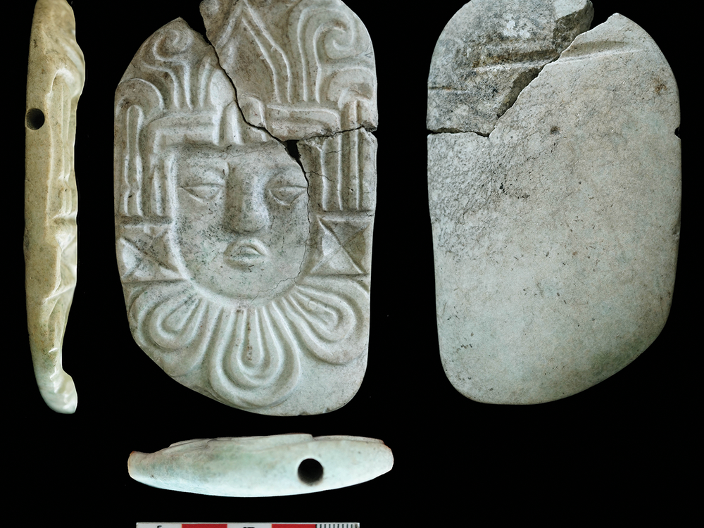 A side, front, back, and top view of a white carved pendant of a human head.