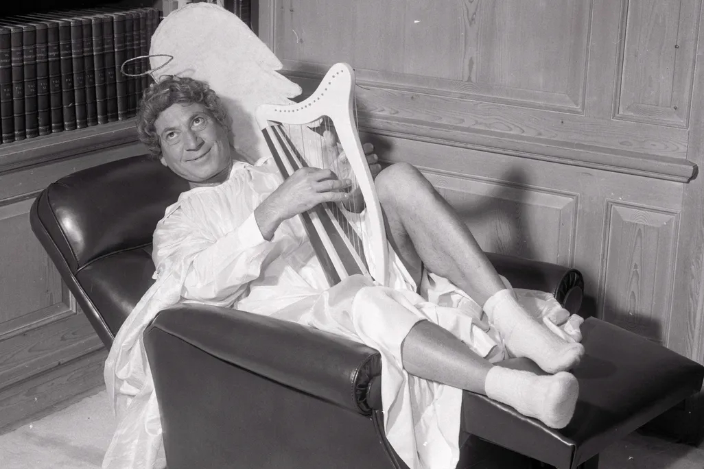 Harpo Marx plays a harp on a couch