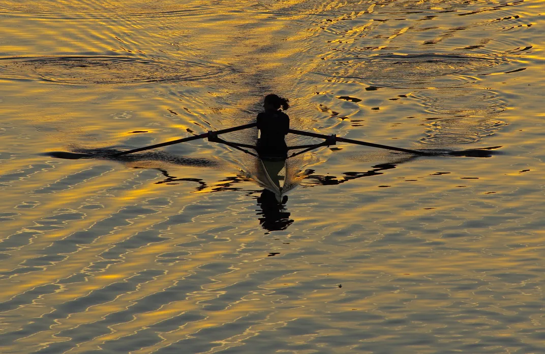 a woman rows on the Charles River