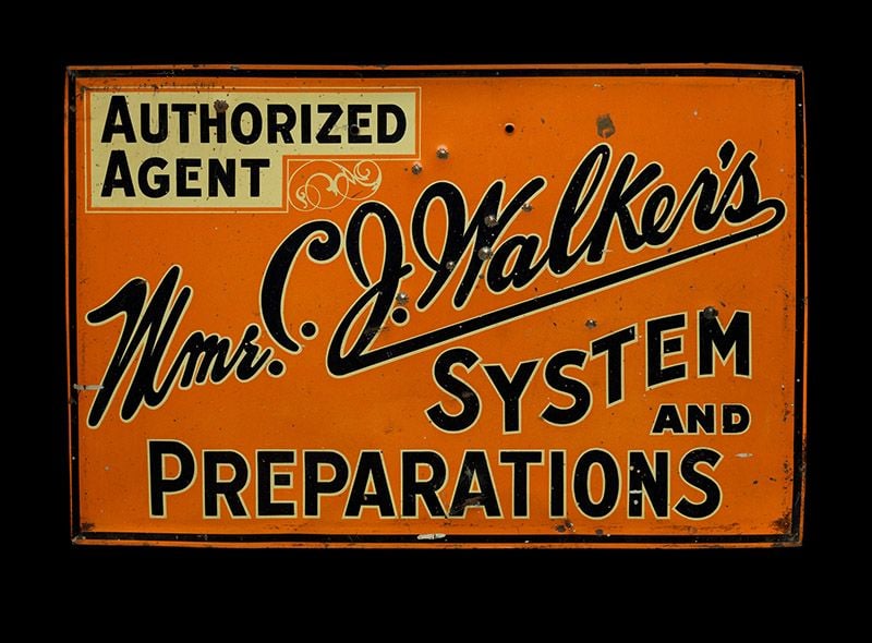 An orange sign with black text reading "Authorized Agent: Mme. C.J. Walker's System and Preparations."