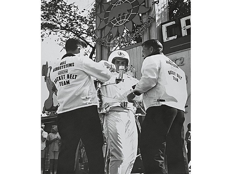 two men helping other man get into a propulsion system suit