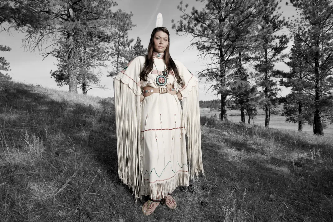 A woman stands among pine trees