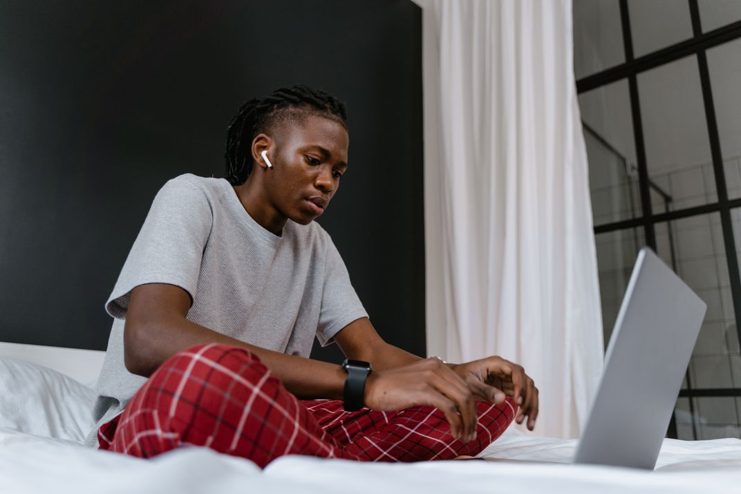 Man wearing AirPods typing on laptop