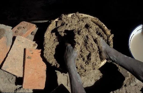 A mason prepares mud mortar.