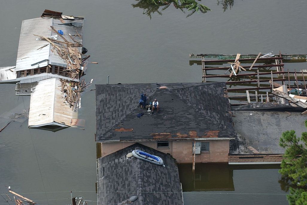 People sit on a roof waiting to be rescued after Hurricane Katrina
