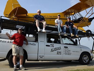 Pilot Greg Koontz (standing) flies an act that depends on the help of his Alabama Boys, Fred Masterson, Jason Hankins, and Walter Harvey (left to right, atop their mobile runway with Koontz’s Piper J-3 Cub).