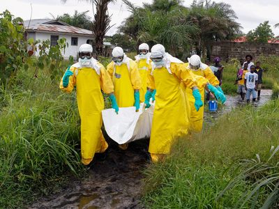 Liberian nurses carry a dead body suspected of dying from the Ebola virus at the Roberts field highway on the outskirts of Monrovia, Liberia, 25 September 2014.