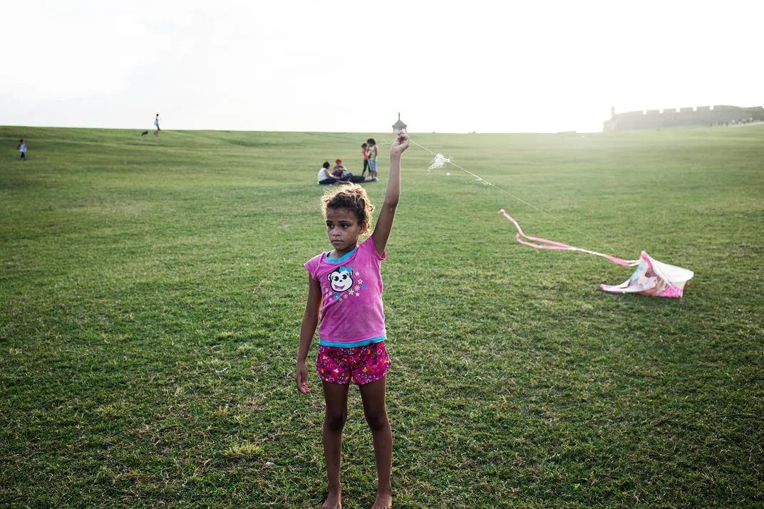 A little girl named Brenda flies a kite at El Morro fort by San Juan Harbor.