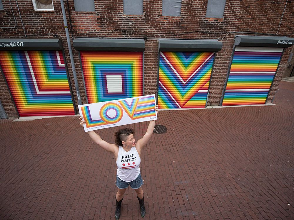 Lisa Marie Thalhammer holds her original LOVE poster with her mural in the background. (Photo by Grant Langford)